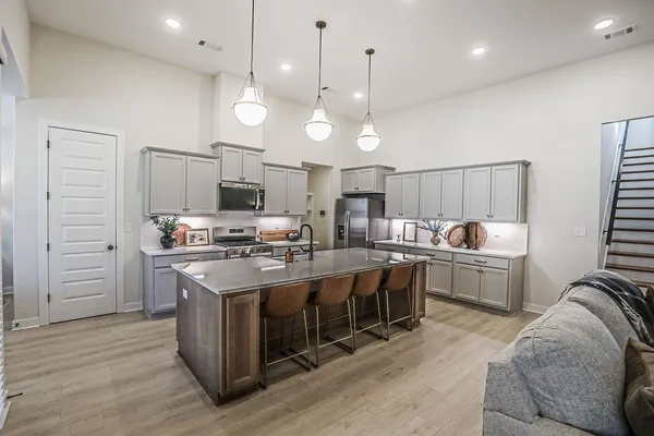 a large kitchen with kitchen island a stove a sink a center island and wooden floor