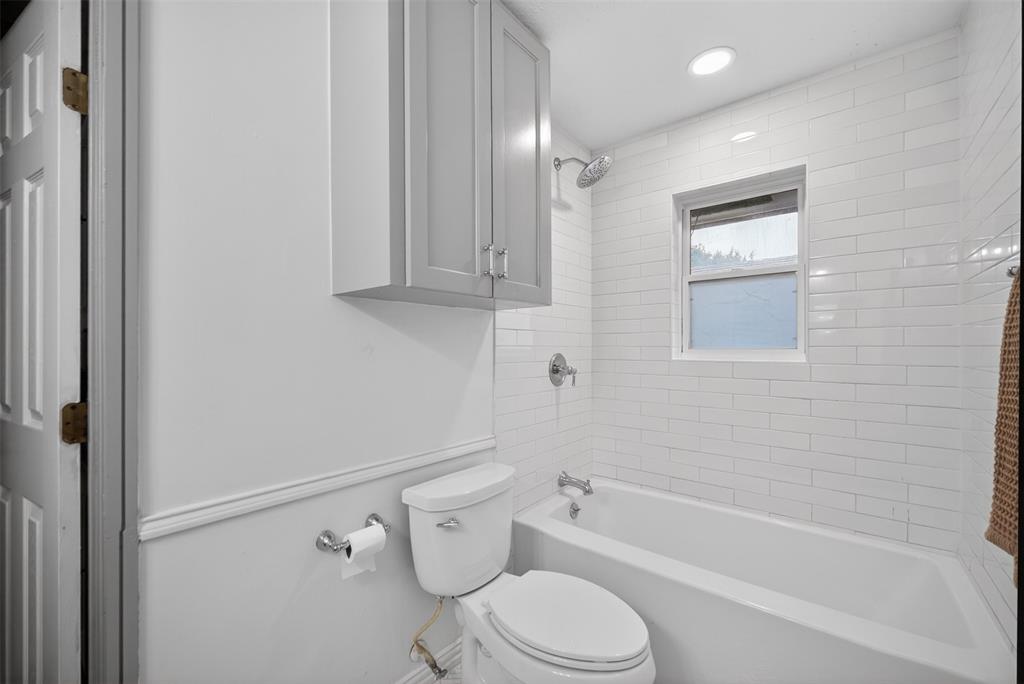 9660 Timberleaf Drive Dallas, TX 75243 - Photo 26 of 40 Bathroom featuring a white bathtub, subway tile surround, recessed lighting, and an overhead storage cabinet with brushed nickel hardware