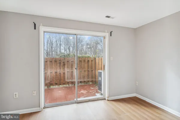 a view of an empty room with wooden floor and door