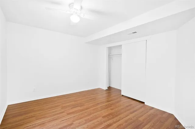 an empty room with wooden floor and fan