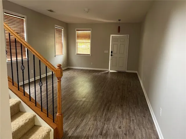 a view of an empty room with wooden floor and stairs