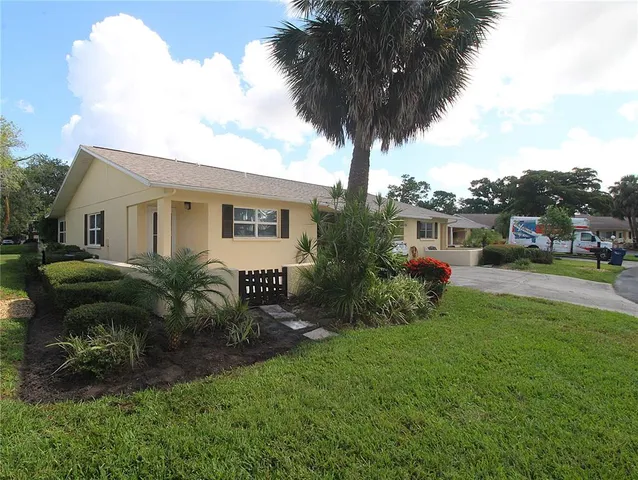 a front view of a house with garden and trees