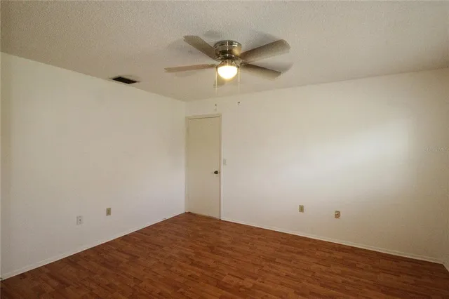 a view of a room with wooden floor and a ceiling fan