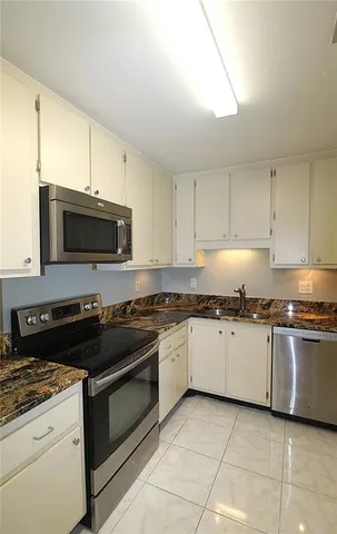 a kitchen with granite countertop a stove top oven microwave and cabinets