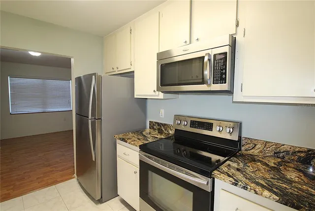 a kitchen with stainless steel appliances white cabinets and a stove top oven