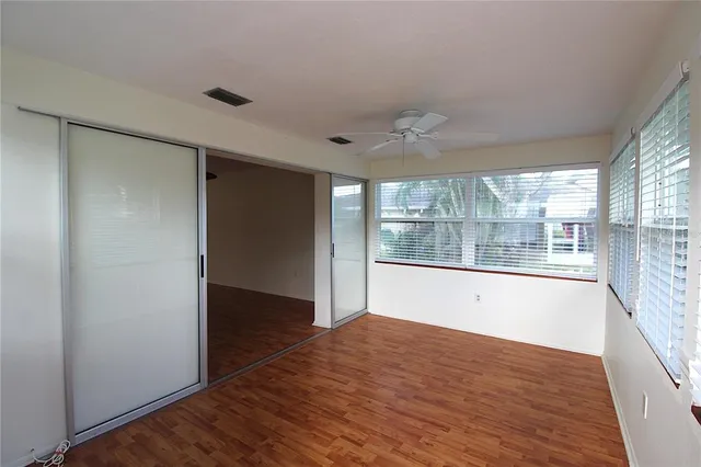 a view of an empty room with wooden floor and a window