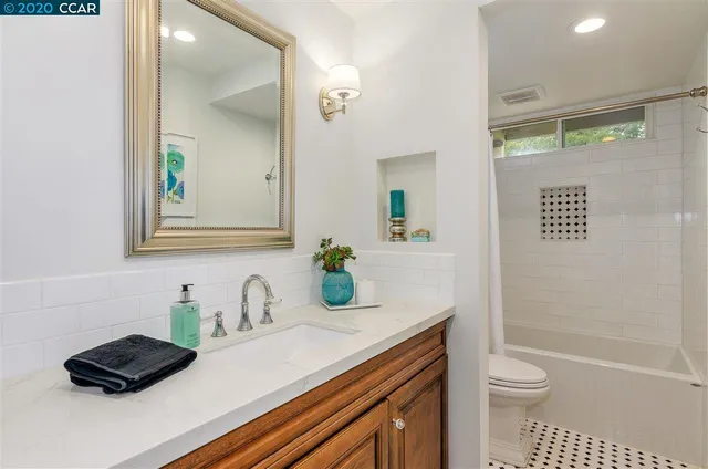 a bathroom with a granite countertop sink a toilet a mirror and shower