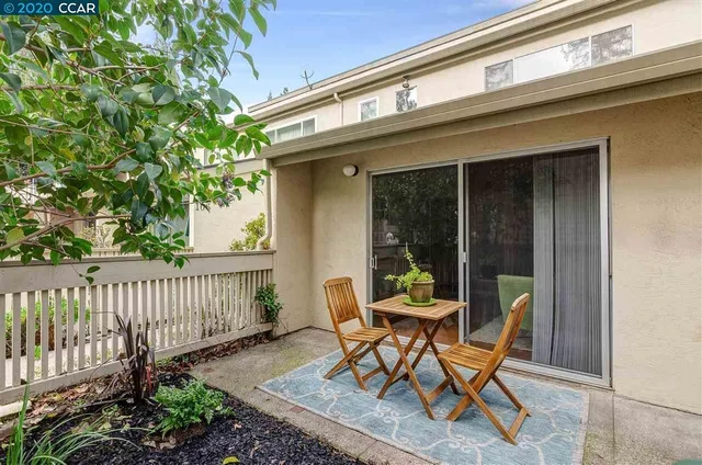 a patio with table and chairs and potted plants