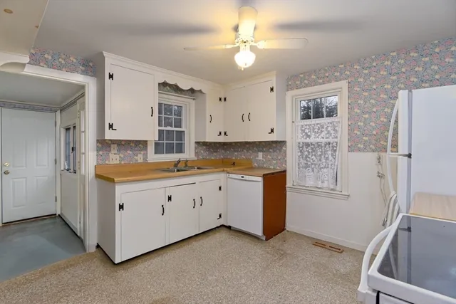 a kitchen with granite countertop a sink cabinets stainless steel appliances and a refrigerator