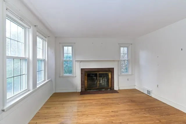 wooden floor fireplace and windows in an empty room