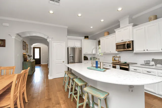 a kitchen with stainless steel appliances granite countertop a sink a stove a refrigerator cabinets and chairs