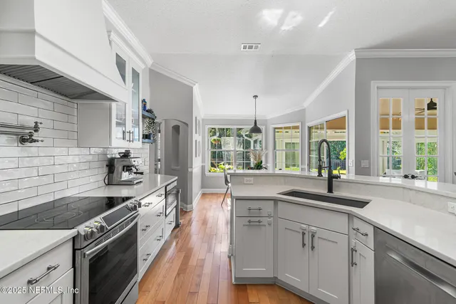 a kitchen with stainless steel appliances granite countertop a sink a stove and cabinets