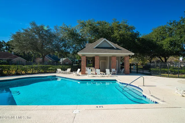 a view of swimming pool with outdoor seating and trees in the background