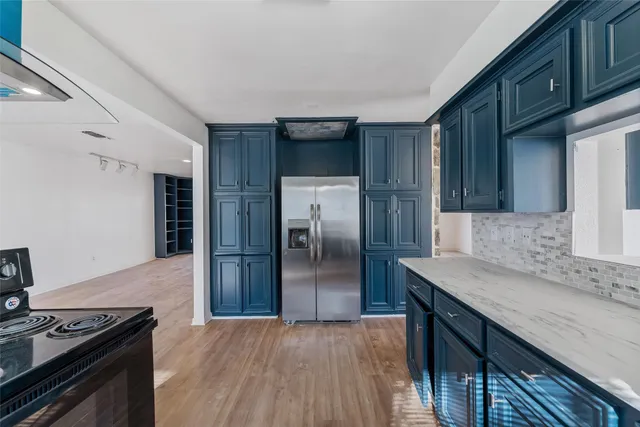 a kitchen with stainless steel appliances granite countertop a refrigerator a stove and a sink with wooden cabinets