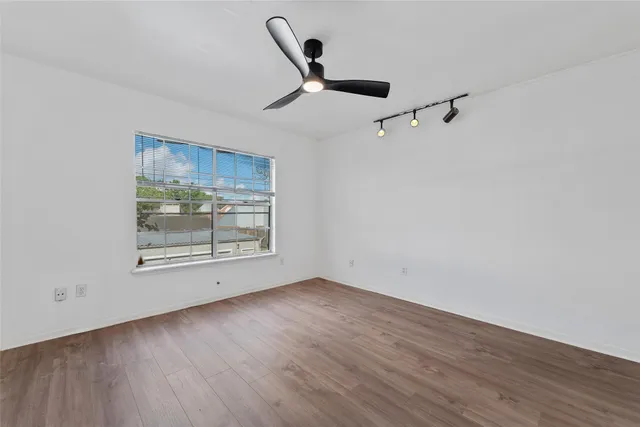 a view of an empty room with wooden floor and window
