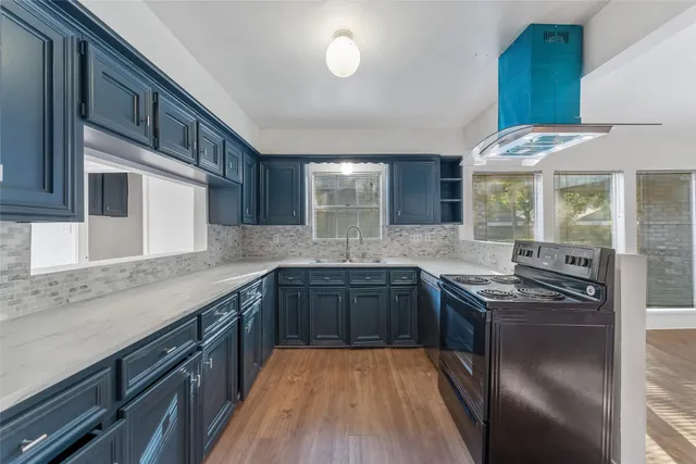 a kitchen with stainless steel appliances granite countertop a sink a stove and a wooden floors