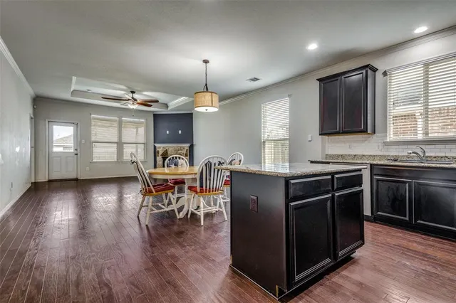 a kitchen with stainless steel appliances granite countertop wooden cabinets a stove a sink a dining table and chairs
