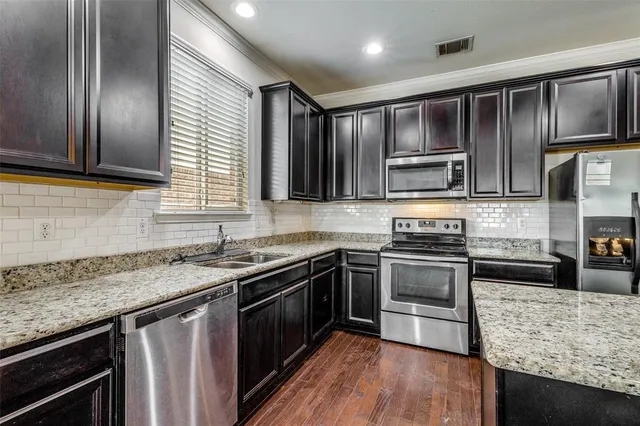 a kitchen with stainless steel appliances granite countertop wooden cabinets a stove top oven a sink and dishwasher