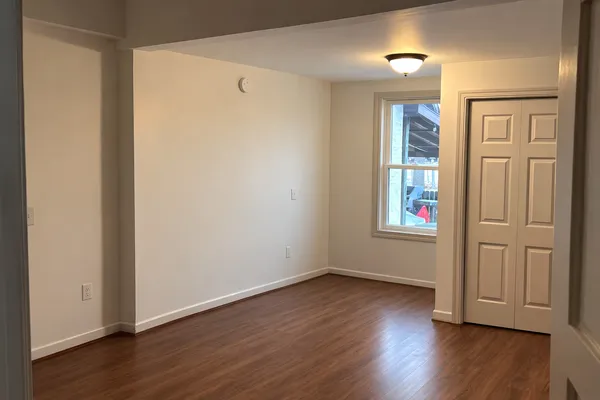 an empty room with wooden floor and windows