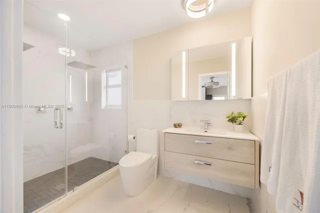 a bathroom with a shower sink vanity and toilet
