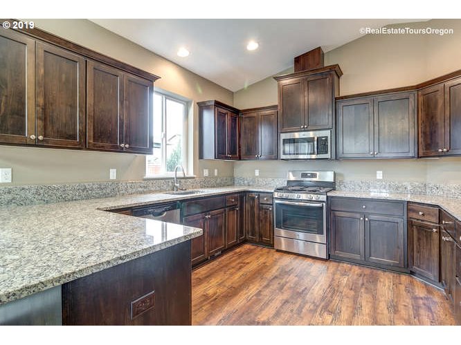 1060 6th Street Gervais, OR 97026 - Photo 16 of 30 a kitchen with stainless steel appliances granite countertop wooden cabinets a stove top oven a sink and dishwasher