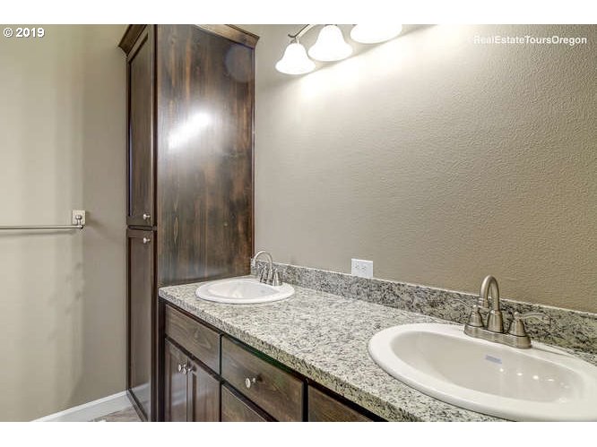 1060 6th Street Gervais, OR 97026 - Photo 23 of 30 a bathroom with a granite countertop sink and a mirror