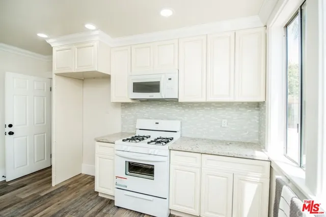 a hall with kitchen island white cabinets and a sink
