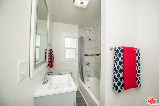 a view of a hallway with wooden floor and a bathroom