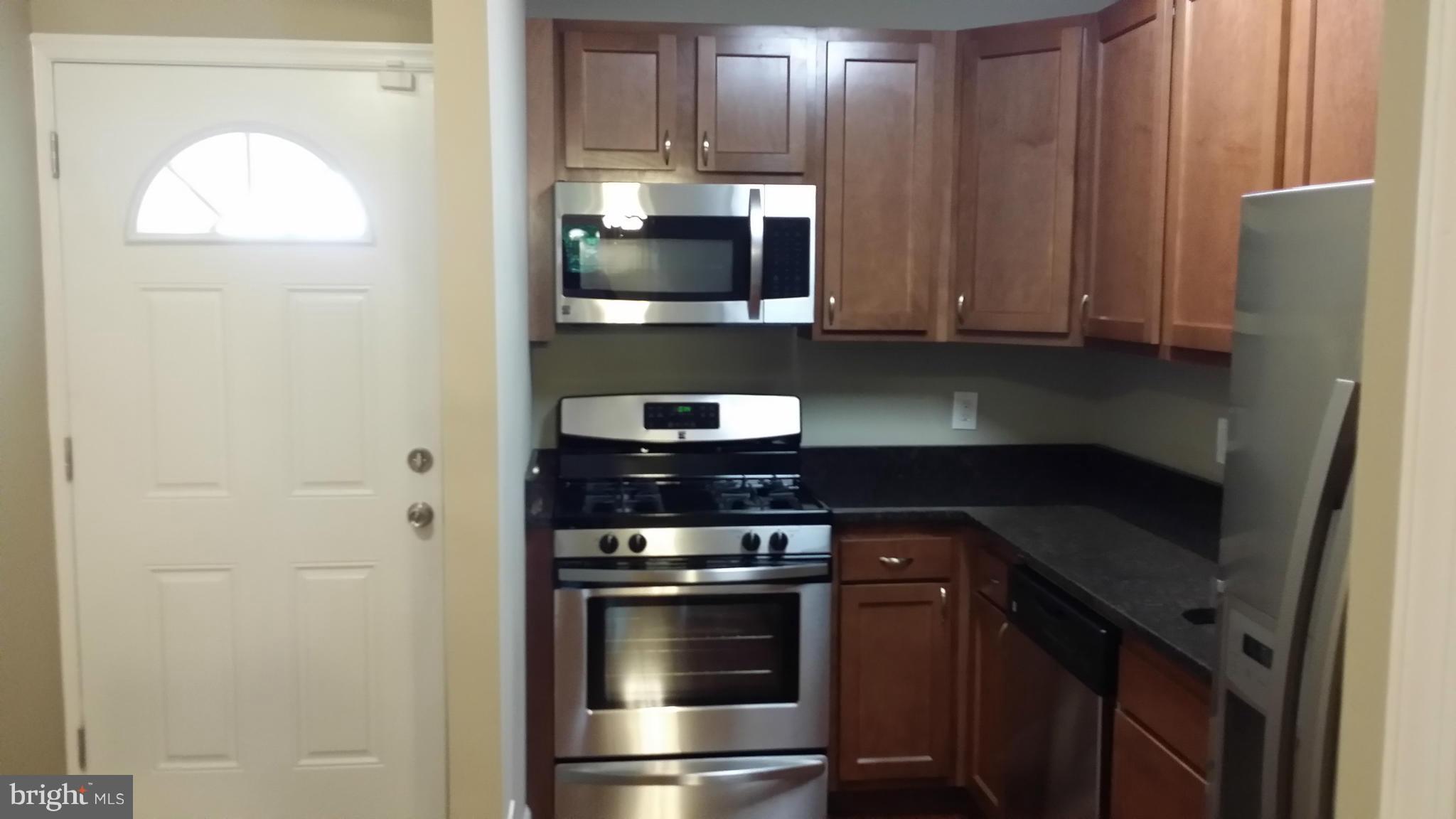 7634 Muncy Road Hyattsville, MD 20785 - Photo 4 of 21 a kitchen with stainless steel appliances granite countertop a stove and a refrigerator with wooden cabinets