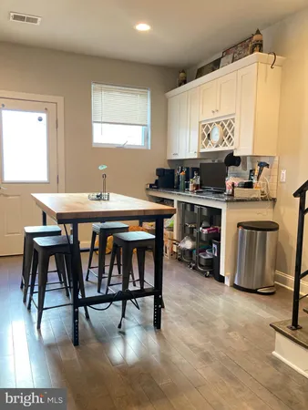 a kitchen with stainless steel appliances a table chairs sink and cabinets