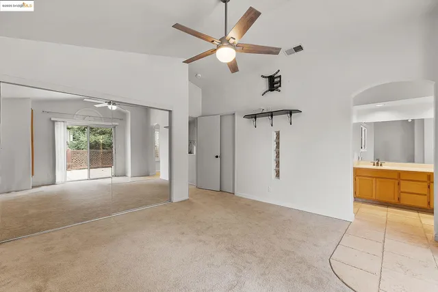 a bedroom with a large bed and a chandelier fan