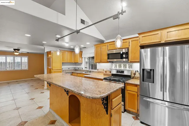 a large kitchen with stainless steel appliances a sink and cabinets
