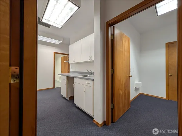 a view of a kitchen with white cabinets and wooden floor