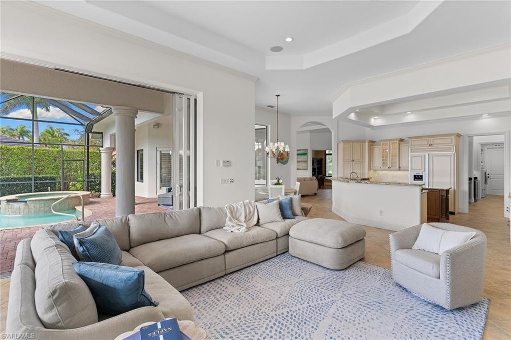 7506 Hogan Court Naples, FL 34113 - Photo 13 of 49 Living room featuring a tray ceiling, a sunroom, and suspended lighting