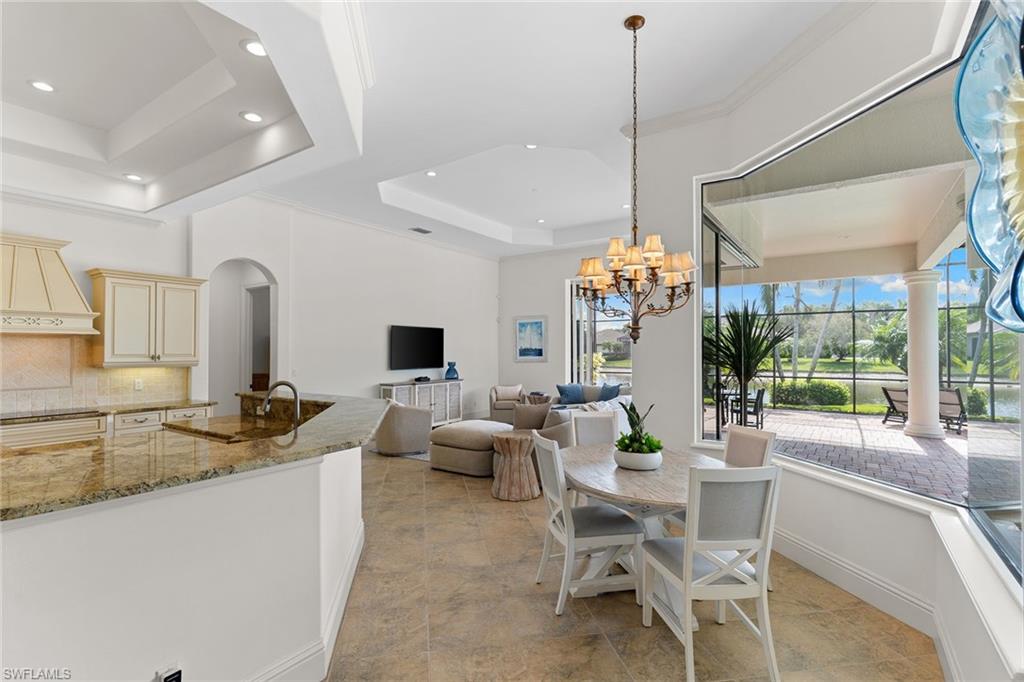 7506 Hogan Court Naples, FL 34113 - Photo 14 of 49 Dining space with a tray ceiling, arched walkways, and a chandelier
