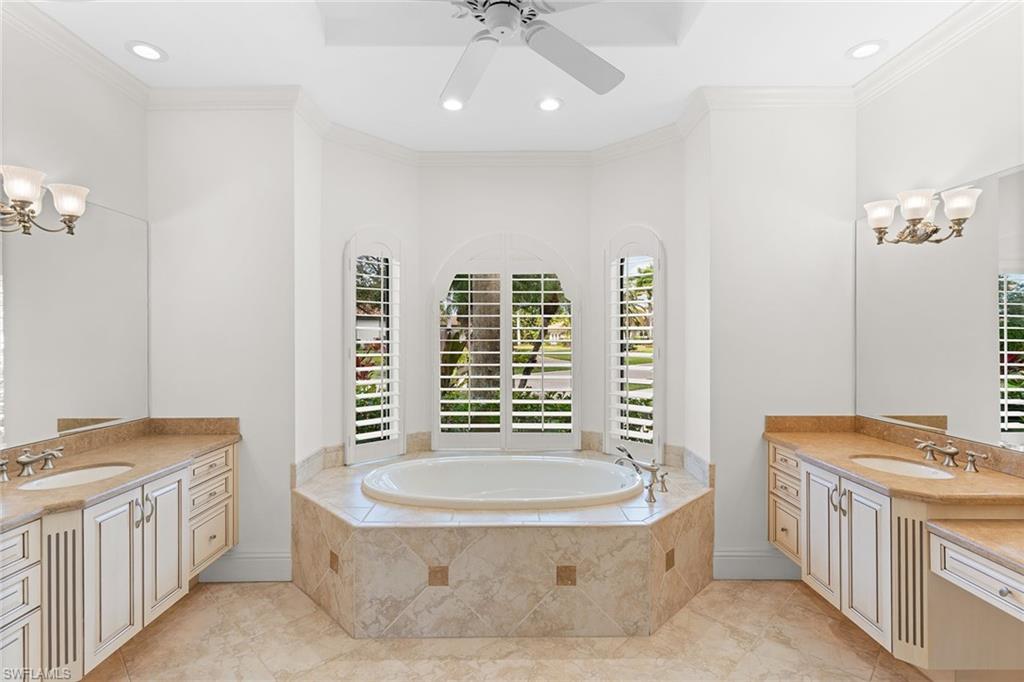 7506 Hogan Court Naples, FL 34113 - Photo 21 of 49 Bathroom with two vanities, a chandelier, ornamental molding, a bath, and a ceiling fan