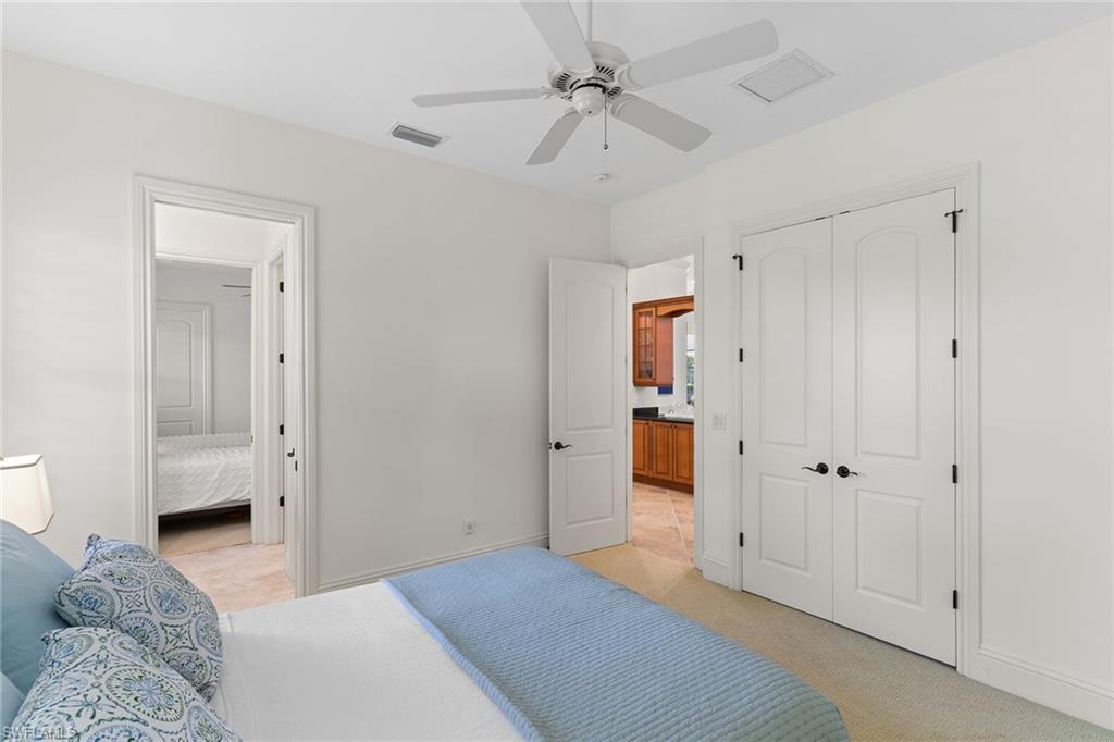 7506 Hogan Court Naples, FL 34113 - Photo 28 of 49 Bedroom with connected bathroom, light colored carpet, a closet, and a ceiling fan