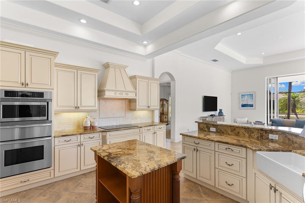 7506 Hogan Court Naples, FL 34113 - Photo 35 of 49 Kitchen with cream cabinets, a raised ceiling, arched walkways, a warming drawer, and stainless steel oven