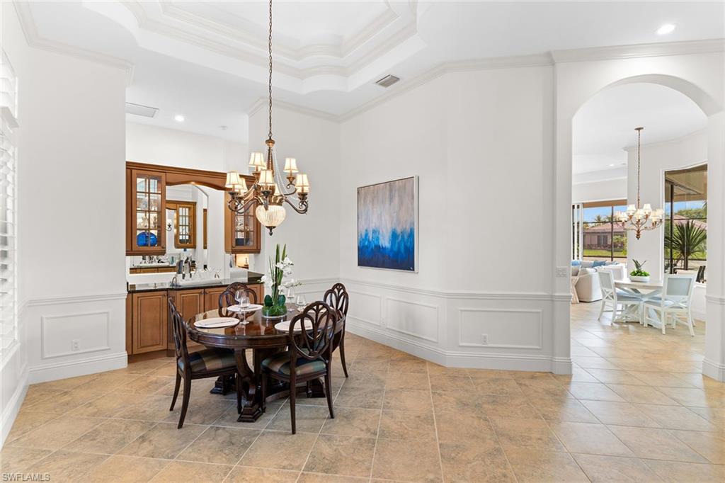 7506 Hogan Court Naples, FL 34113 - Photo 41 of 49 Dining area featuring suspended lighting, arched walkways, crown molding, and a wainscoted wall
