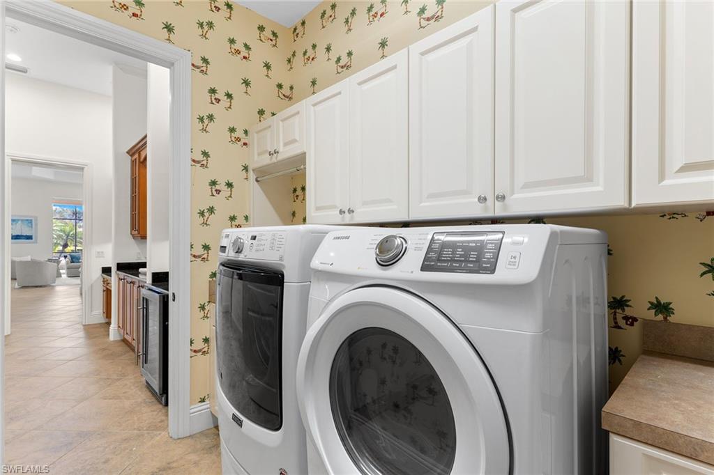7506 Hogan Court Naples, FL 34113 - Photo 42 of 49 Laundry area with beverage cooler, cabinet space, wallpapered walls, washer and clothes dryer, and light tile patterned flooring