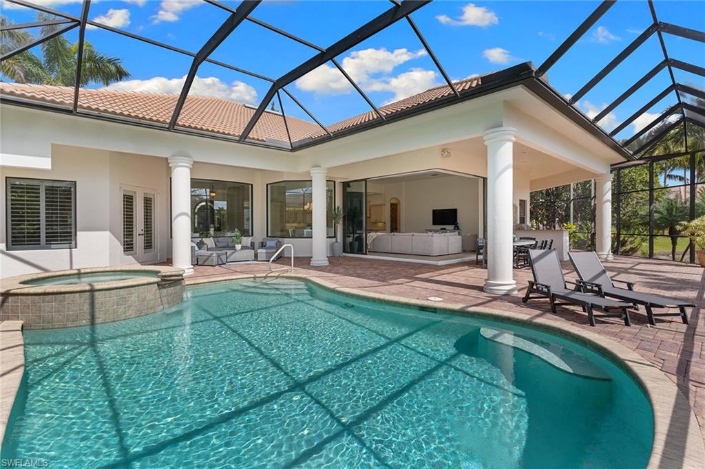 7506 Hogan Court Naples, FL 34113 - Photo 9 of 49 Combined pool / hot tub featuring a sunroom, glass enclosure, a patio area, and an outdoor kitchen