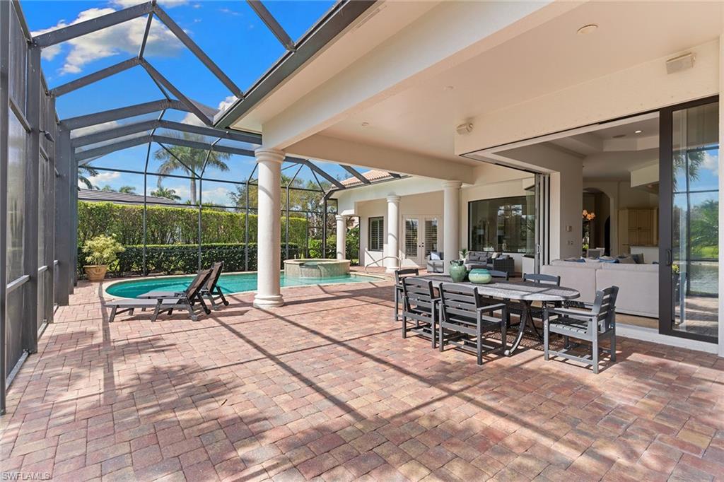 7506 Hogan Court Naples, FL 34113 - Photo 10 of 49 View of patio with outdoor dining area, a sunroom, glass enclosure, and a pool with connected hot tub
