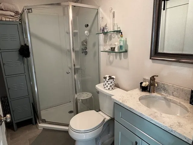 a bathroom with a granite countertop sink toilet and shower