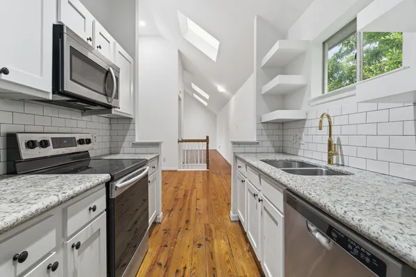 a kitchen with stainless steel appliances granite countertop a kitchen island a stove a sink and a microwave