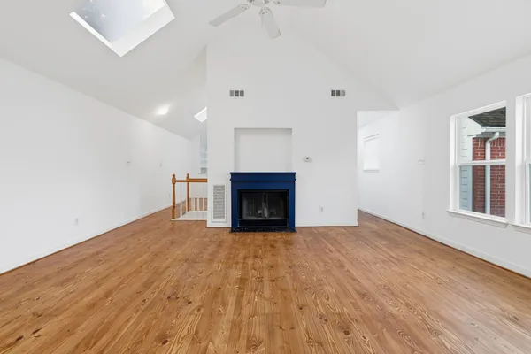a view of an empty room with wooden floor fireplace and a window