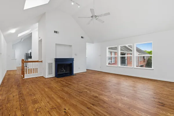 a view of an empty room with wooden floor fireplace and a window