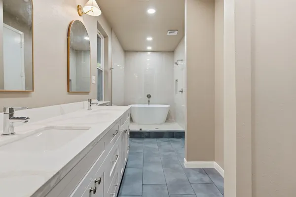 a spacious bathroom with a double vanity sink a mirror and a