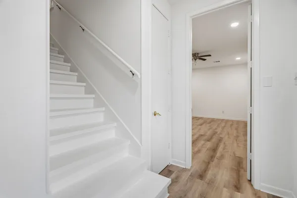 a view of a hallway with wooden floor and staircase