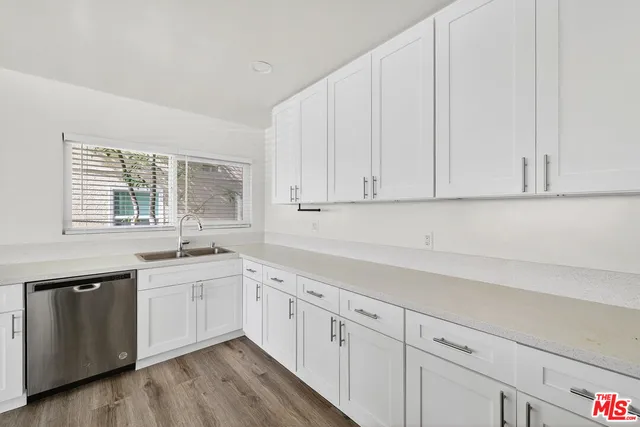 a kitchen with white cabinets and sink