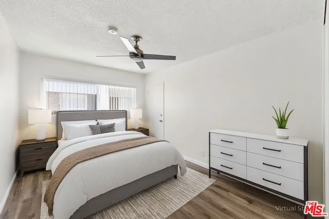 a bedroom with a bed and a potted plant on the dresser